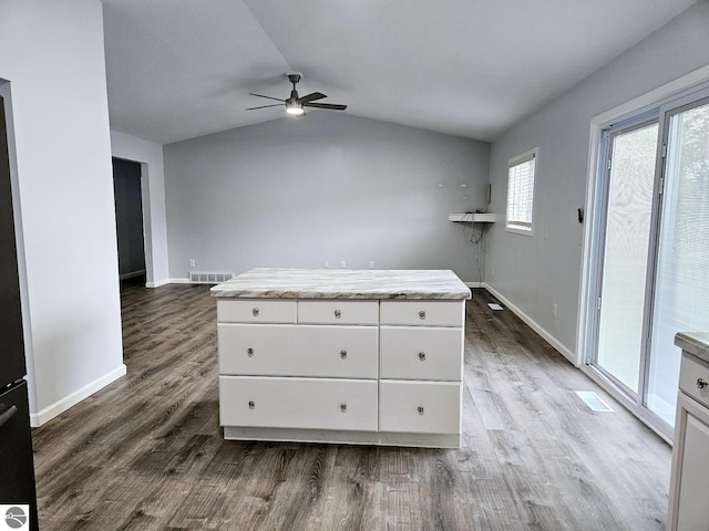 interior space featuring visible vents, a ceiling fan, dark wood finished floors, baseboards, and vaulted ceiling