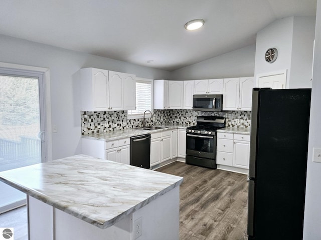 kitchen with white cabinetry, vaulted ceiling, appliances with stainless steel finishes, and a sink