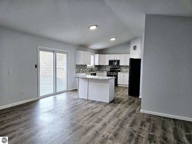 kitchen featuring lofted ceiling, dark wood-style flooring, black appliances, white cabinetry, and backsplash