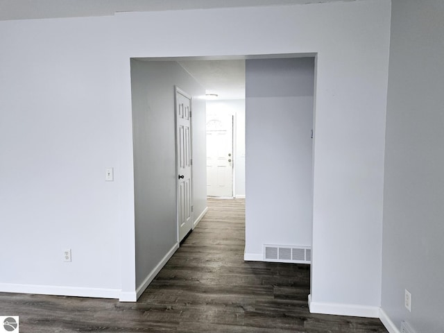 corridor with baseboards, visible vents, and dark wood-style flooring