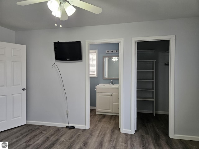 unfurnished bedroom with a walk in closet, ensuite bath, dark wood-style floors, a closet, and baseboards