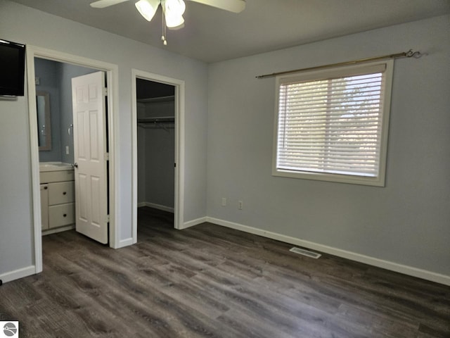 unfurnished bedroom with visible vents, baseboards, a spacious closet, and dark wood-style flooring