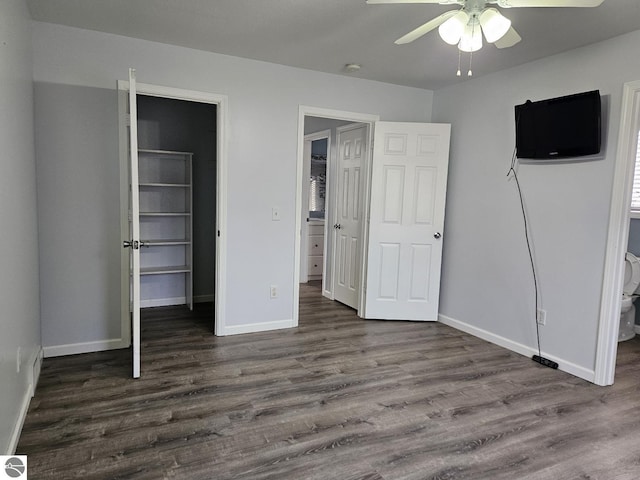 unfurnished bedroom featuring a closet, ceiling fan, baseboards, and dark wood-style flooring