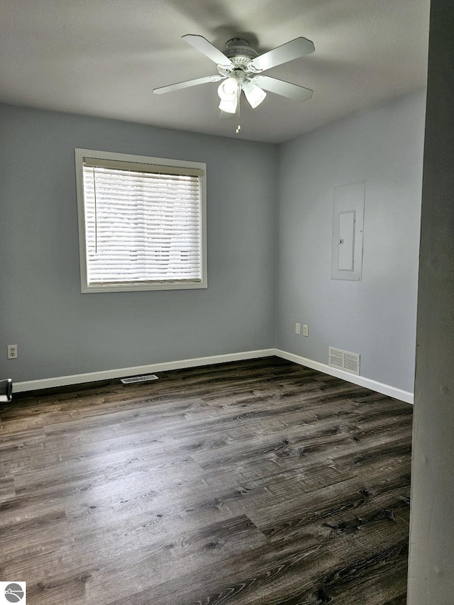 spare room with visible vents, ceiling fan, baseboards, electric panel, and dark wood-style floors