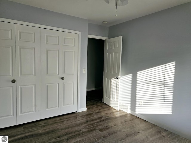 unfurnished bedroom with a closet, ceiling fan, baseboards, and dark wood-style flooring