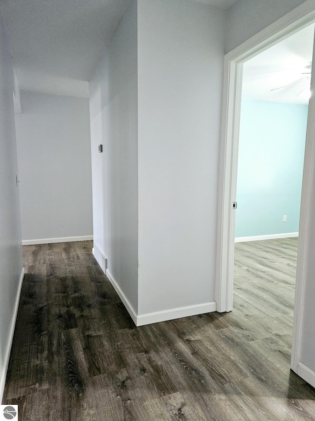 corridor with baseboards and wood finished floors