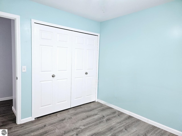 unfurnished bedroom with a closet, baseboards, and wood finished floors