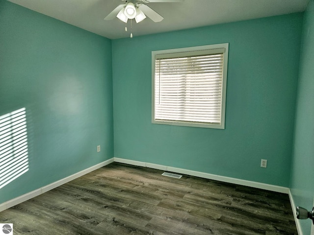 empty room featuring dark wood-type flooring, baseboards, visible vents, and ceiling fan