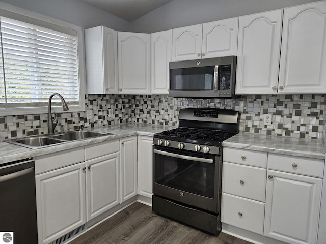 kitchen with tasteful backsplash, dark wood-style floors, white cabinets, stainless steel appliances, and a sink