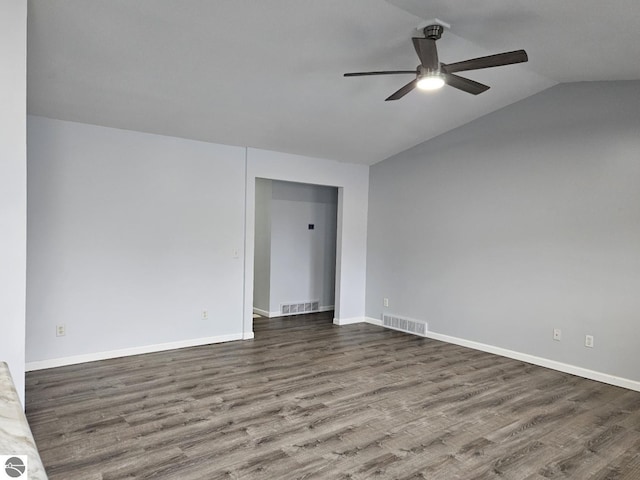 spare room featuring visible vents, dark wood-type flooring, and lofted ceiling