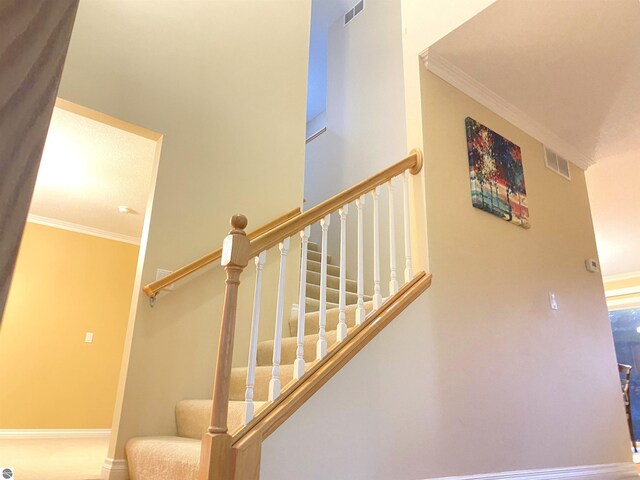 stairway featuring visible vents, baseboards, and ornamental molding