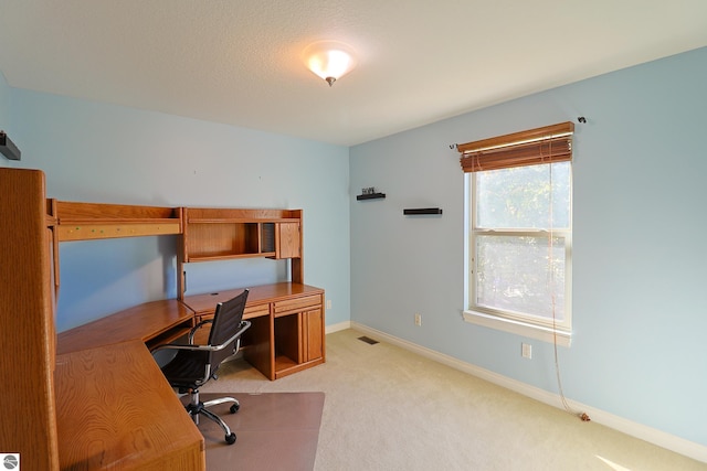 home office featuring baseboards, visible vents, and light carpet