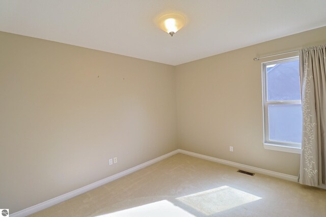 unfurnished room with baseboards, visible vents, and light carpet