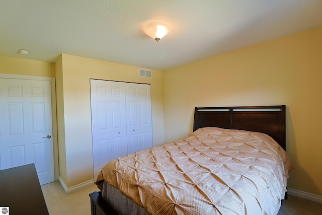 bedroom with visible vents, baseboards, light colored carpet, and a closet