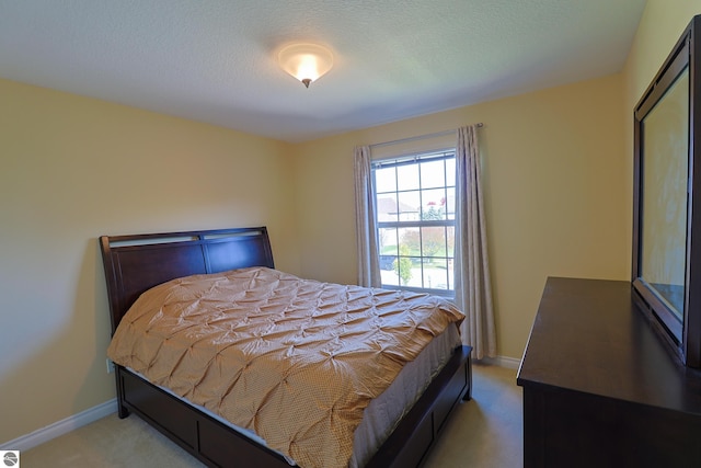 bedroom featuring baseboards, light colored carpet, and a textured ceiling