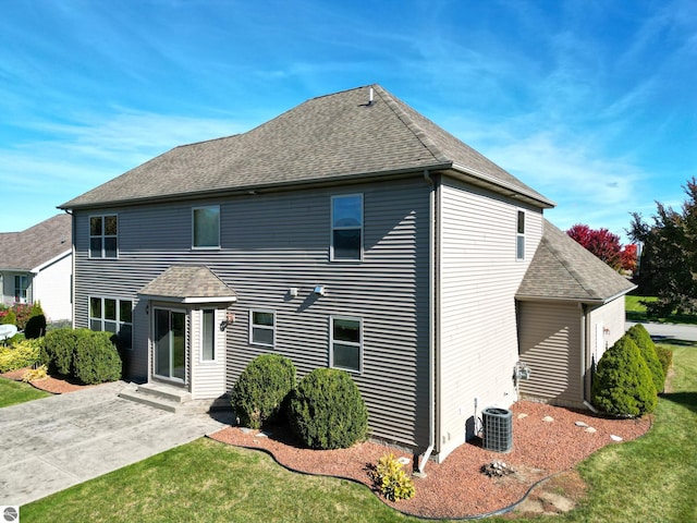 view of front of house with a patio area, a front lawn, a shingled roof, and central AC