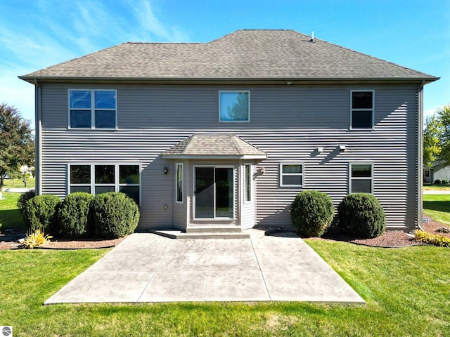 back of house with a yard, a patio area, and roof with shingles