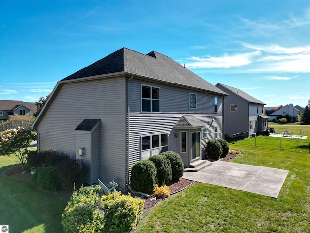 view of front of house featuring entry steps, a front lawn, a patio area, and a shingled roof