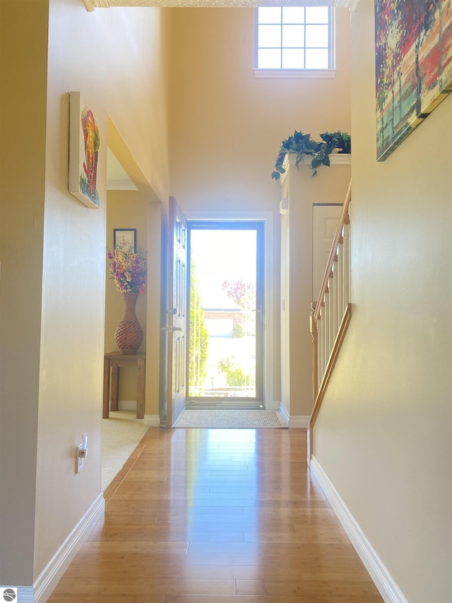 foyer with stairway, wood finished floors, baseboards, and a towering ceiling