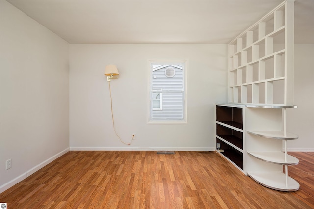 unfurnished room with light wood-type flooring and baseboards