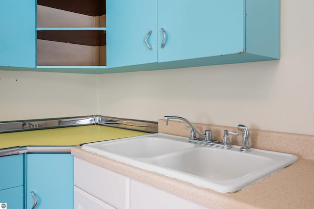 kitchen with a sink, blue cabinets, and light countertops