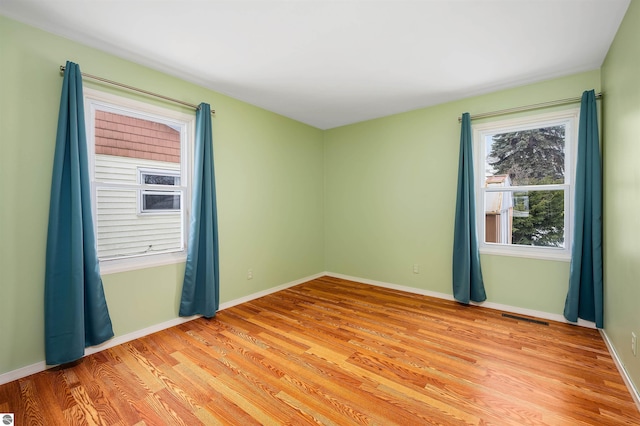 empty room with visible vents, baseboards, and light wood-style floors