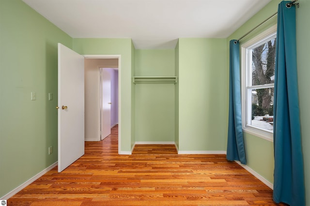 unfurnished bedroom with light wood-type flooring, baseboards, and a closet