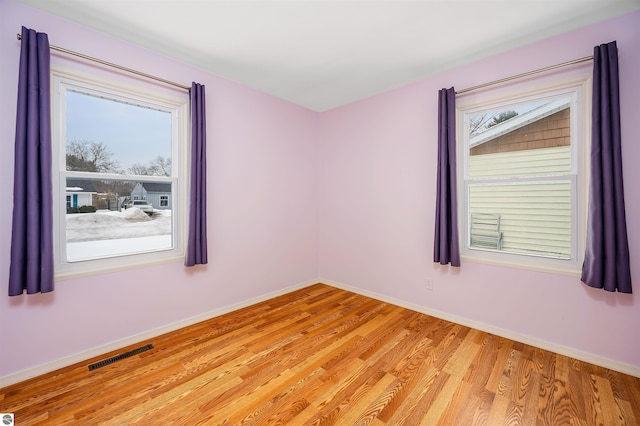 spare room with baseboards, visible vents, and light wood finished floors