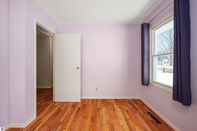 unfurnished room with visible vents, light wood-style flooring, and baseboards