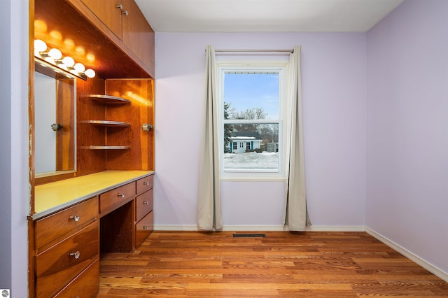 interior space featuring light wood-style flooring, visible vents, baseboards, and built in desk