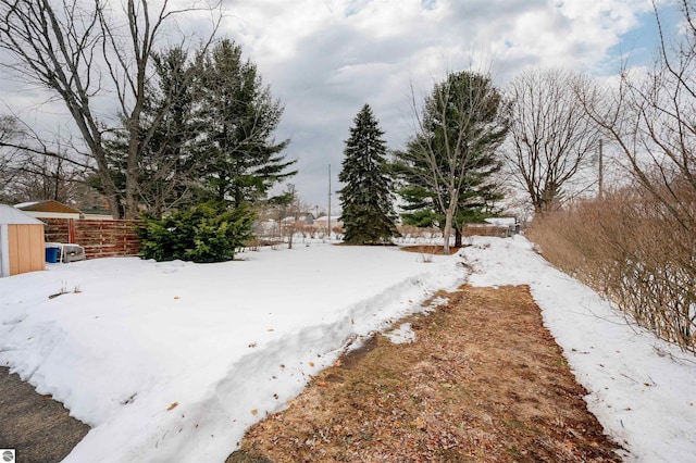 snowy yard featuring an outbuilding and fence