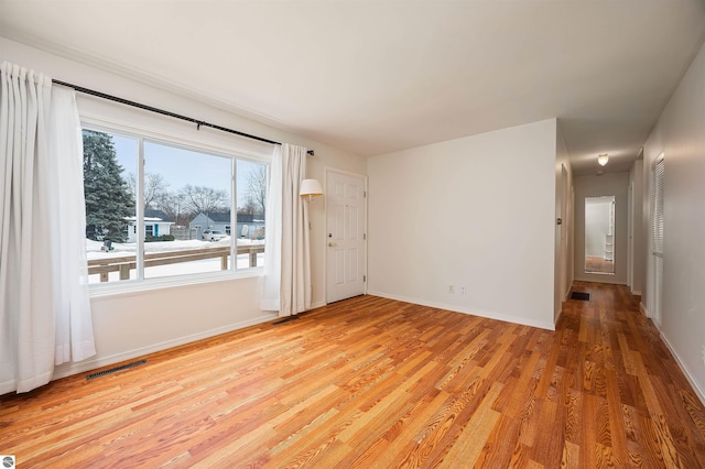 unfurnished room featuring light wood-style floors, visible vents, and baseboards