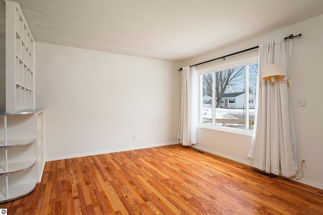 empty room featuring visible vents, baseboards, and light wood-style floors