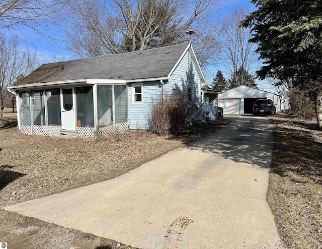 view of front facade with a garage, driveway, an outdoor structure, and roof with shingles