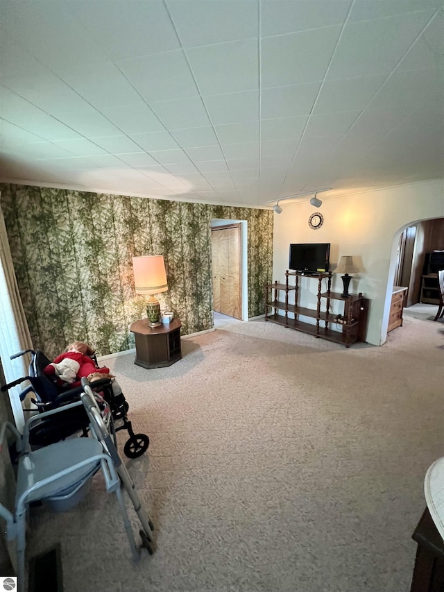 living area with arched walkways, carpet flooring, and wallpapered walls