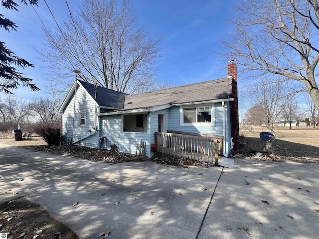 view of front of property featuring roof with shingles, driveway, and a chimney