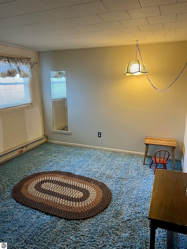 interior space with a baseboard heating unit, baseboards, and carpet flooring