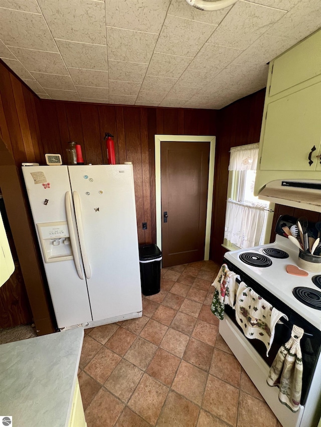 kitchen featuring green cabinets, white refrigerator with ice dispenser, wood walls, and electric range oven