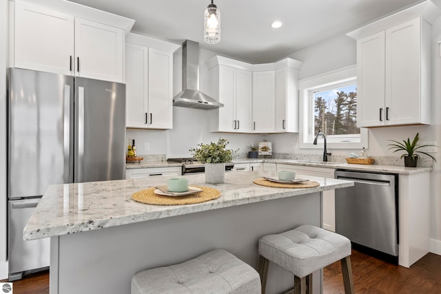 kitchen with a sink, stainless steel appliances, wall chimney exhaust hood, and white cabinets