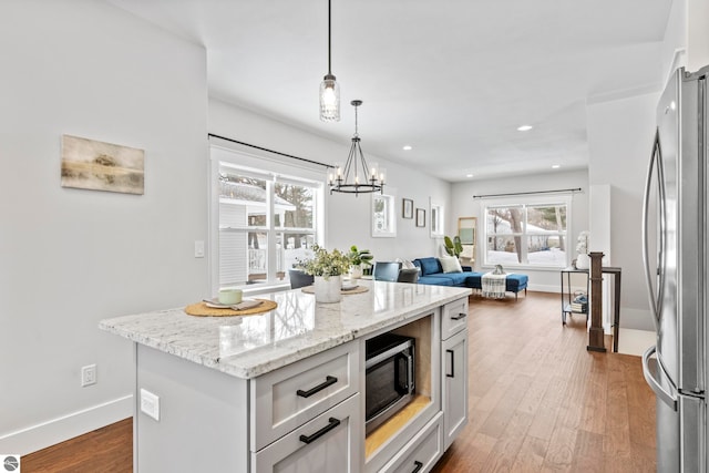 kitchen with light stone counters, a kitchen island, dark wood finished floors, recessed lighting, and appliances with stainless steel finishes