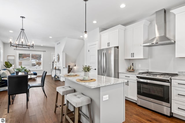 kitchen featuring a kitchen island, dark wood finished floors, stainless steel appliances, white cabinetry, and wall chimney range hood