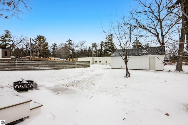 yard layered in snow with an outdoor structure and fence