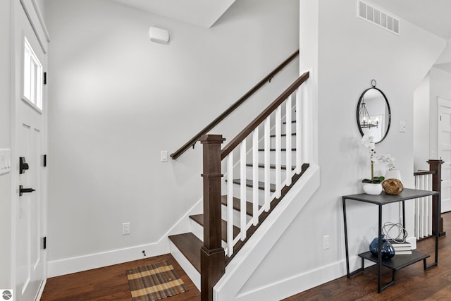 stairway featuring visible vents, baseboards, and wood finished floors