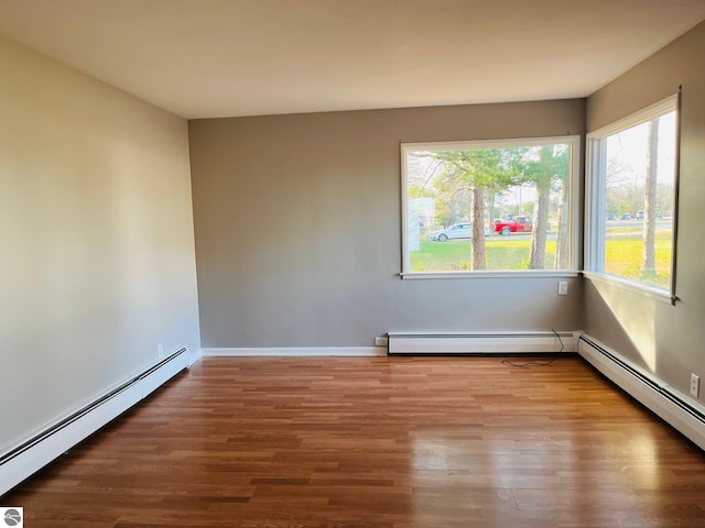 unfurnished room featuring a baseboard heating unit and wood finished floors