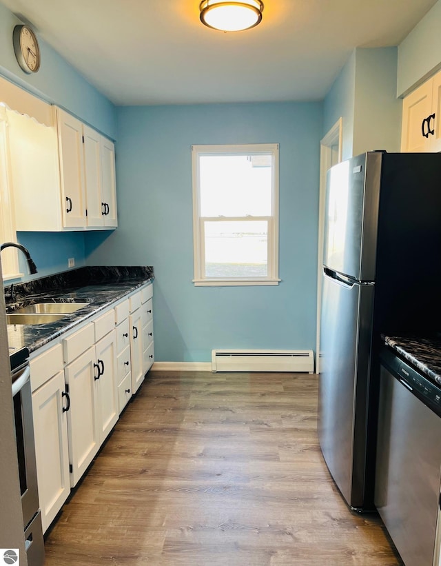 kitchen with light wood finished floors, appliances with stainless steel finishes, a baseboard heating unit, and a sink