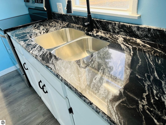 interior details with stainless steel electric range oven, dark wood-style flooring, a sink, white cabinets, and dark countertops