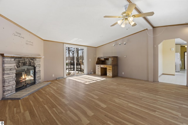 unfurnished living room with visible vents, ornamental molding, wood finished floors, a stone fireplace, and vaulted ceiling