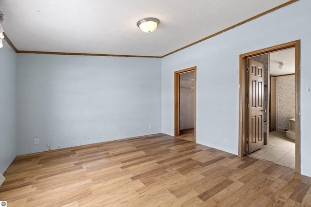 empty room with crown molding and light wood finished floors