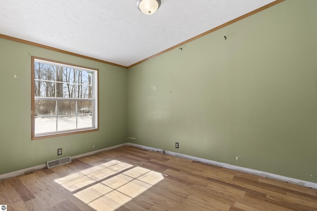 unfurnished room with visible vents, crown molding, baseboards, and wood finished floors