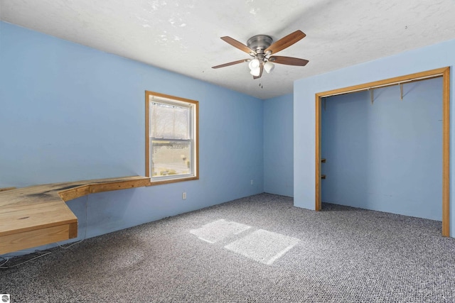 unfurnished bedroom with carpet flooring, a ceiling fan, a closet, and a textured ceiling